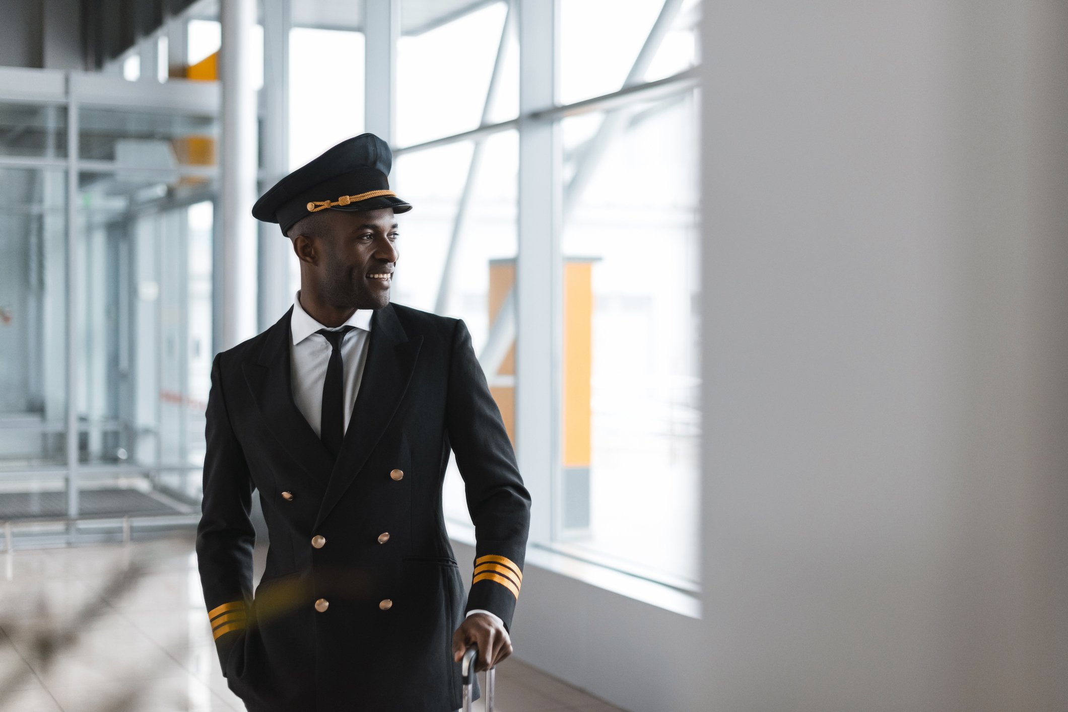 A smiling pilot in an airport concourse.