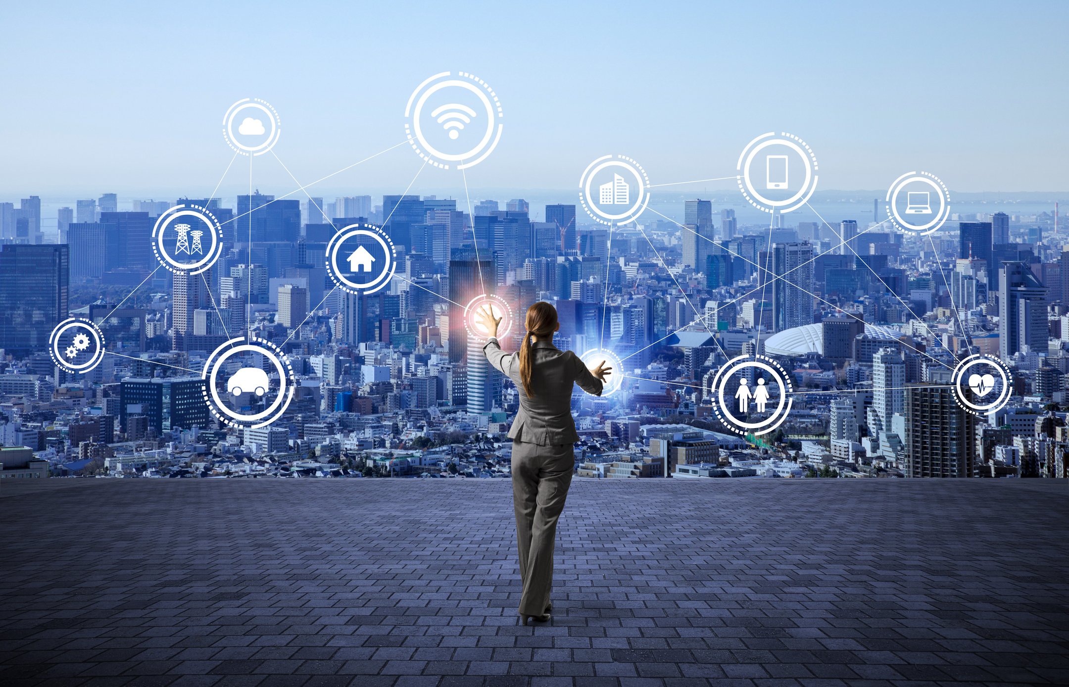 A woman in a city landscape surrounded by connected icons featuring devices, a house, people, a clock, and modes of transportation.