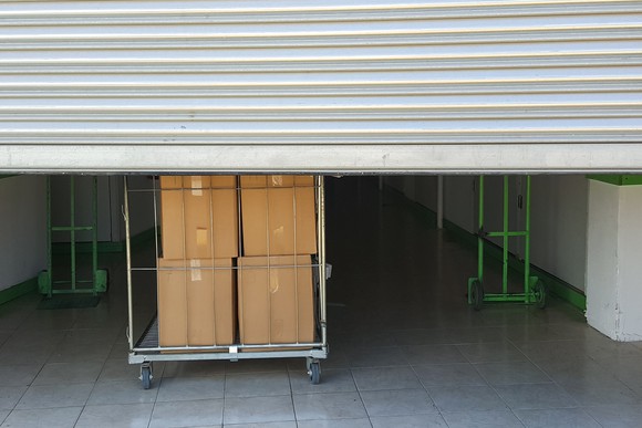 A storage unit with the door drawn halfway up where boxes can be seen inside.