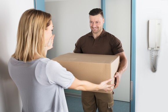 A woman excepting a package from a delivery man.