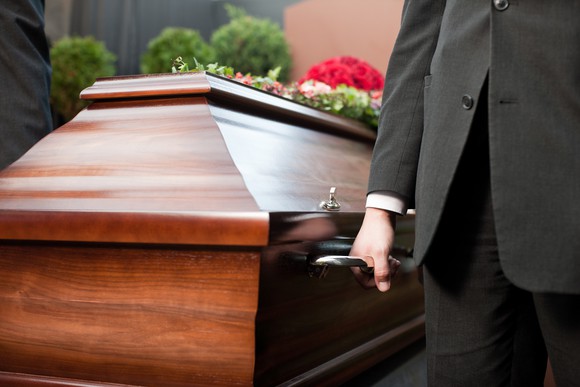Pallbearer holding onto a wooden casket