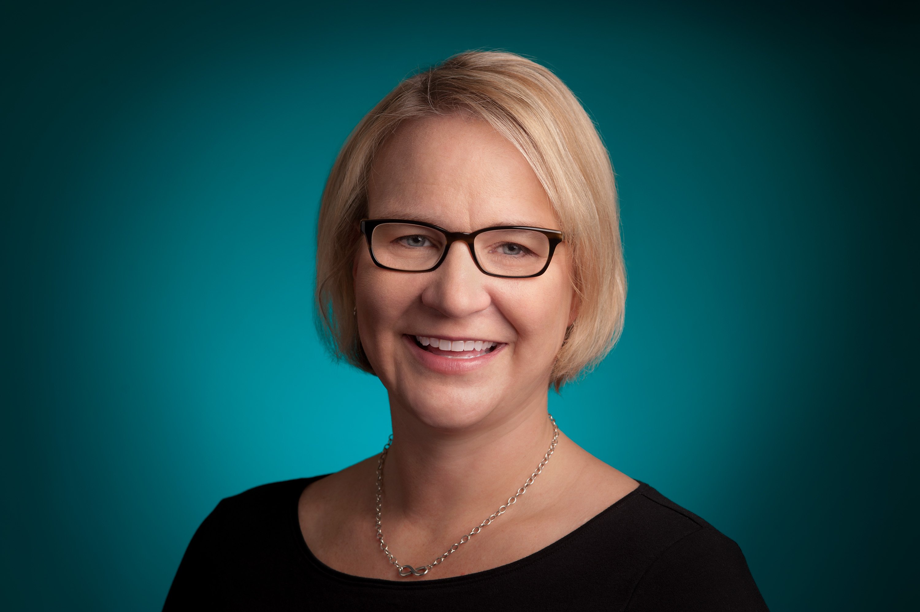 Suzanne Frey smiling at camera in front of green background.