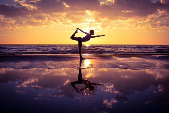 Woman doing yoga on beach in the early morning.
