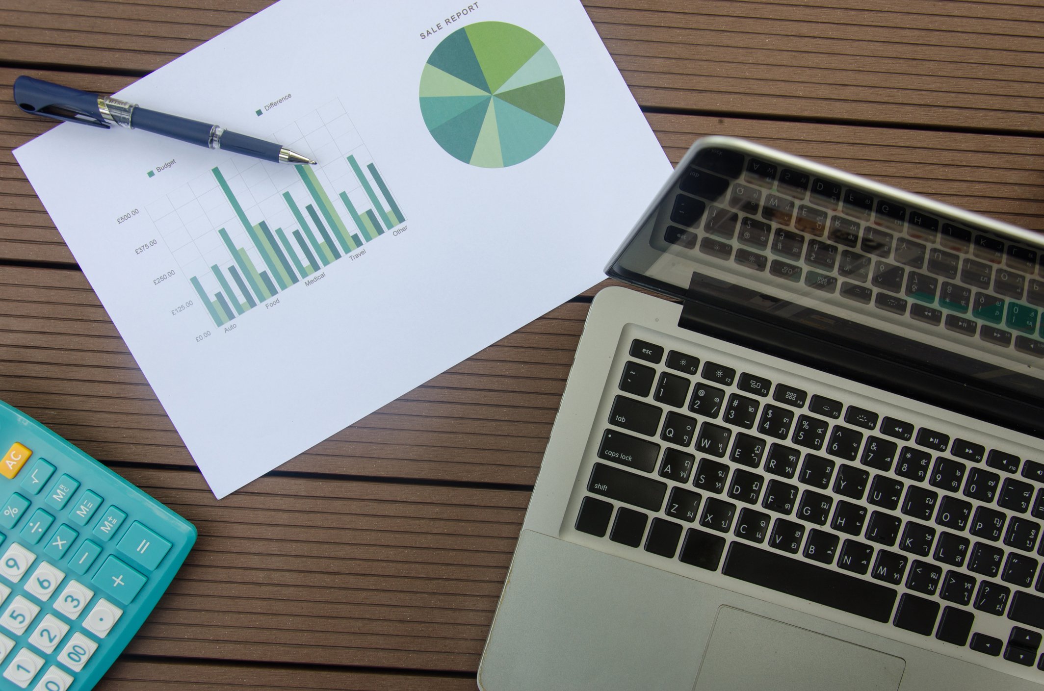 A paper with a bar chart and pie chart next to a laptop