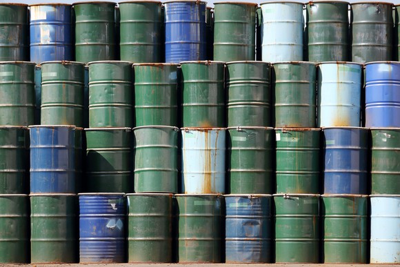 Four layers of green and blue oil barrels stacked up.