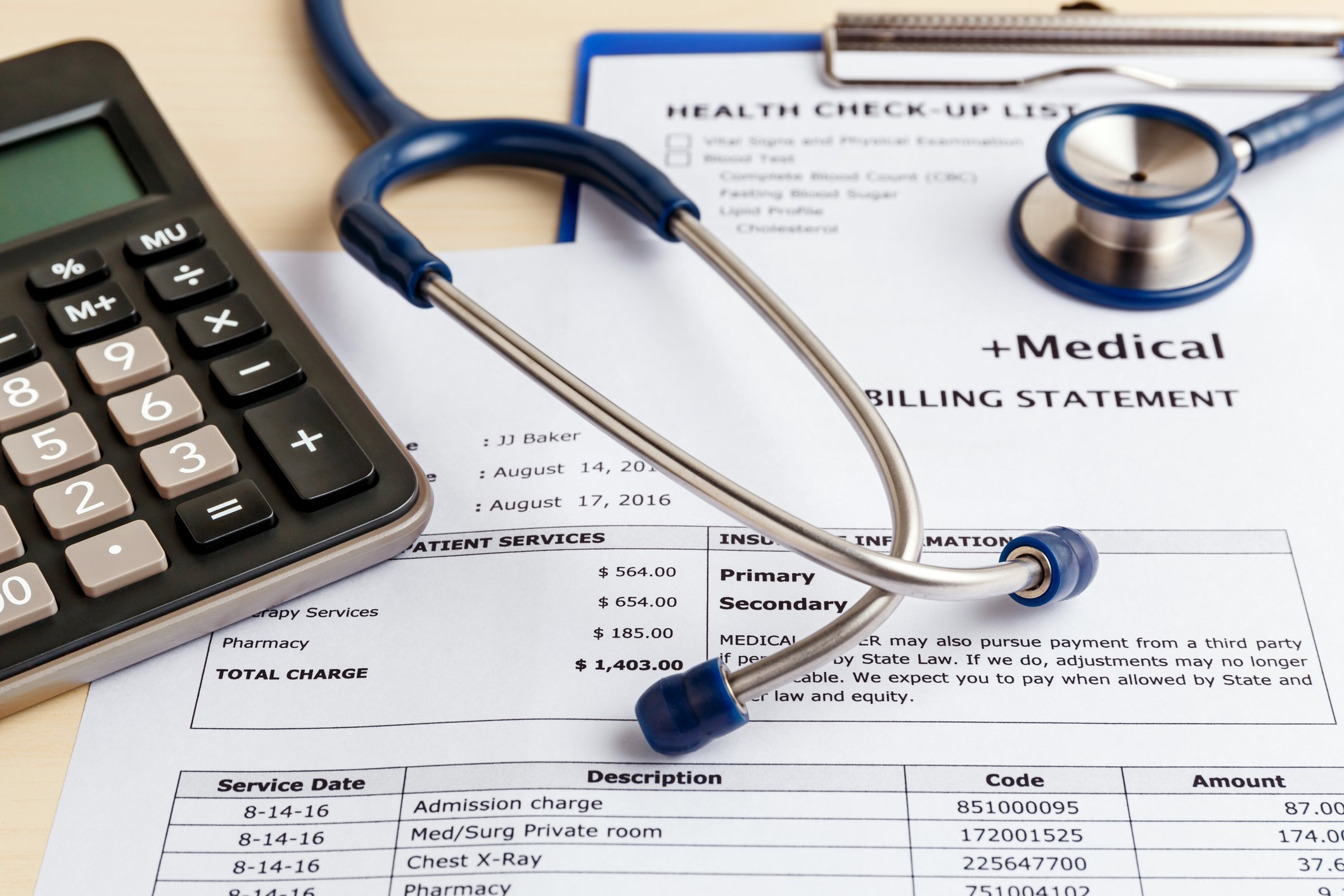 A stethoscope sits on top of a medical bill, next to a calculator.