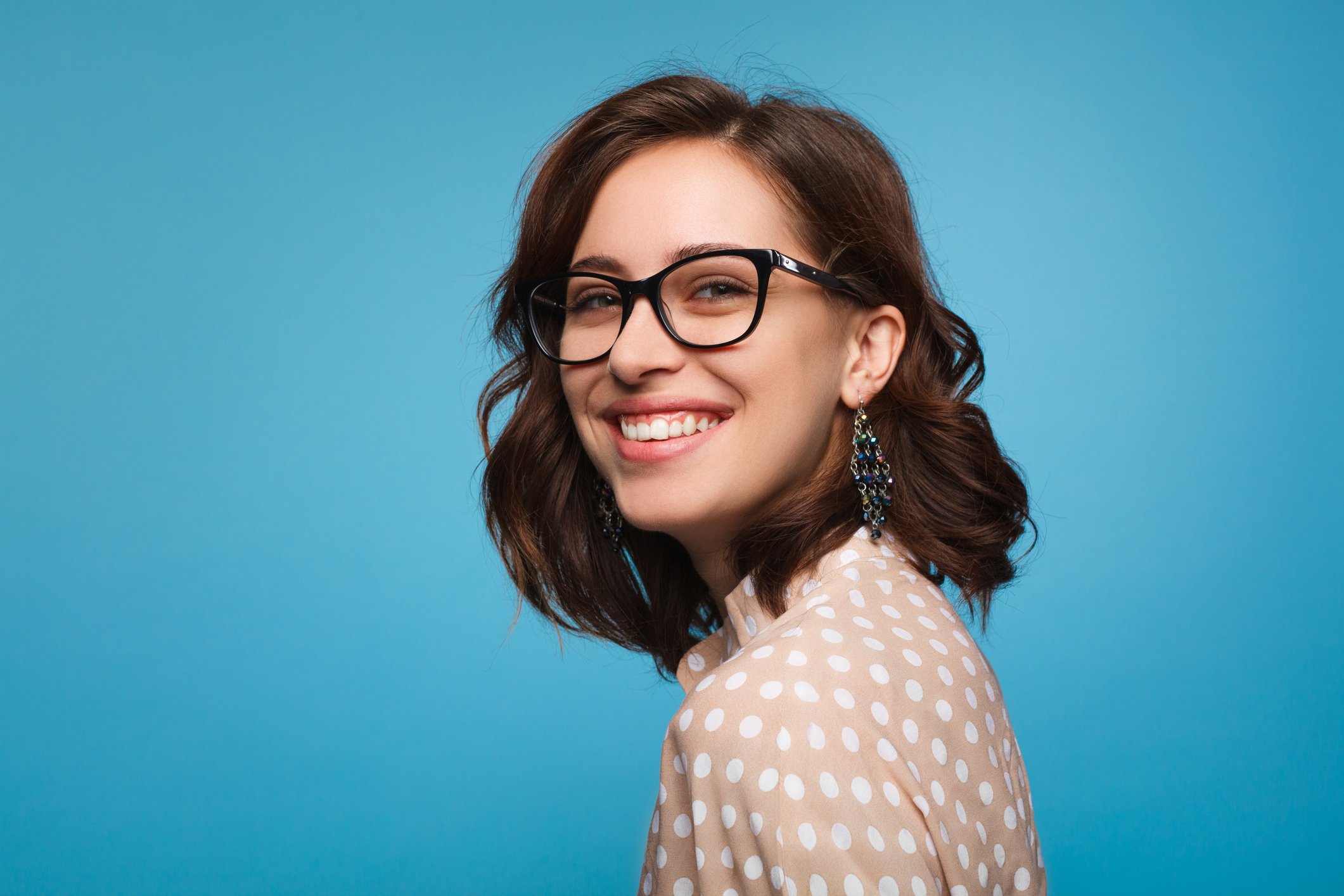 A smiling girl wearing glasses and looking at the camera.