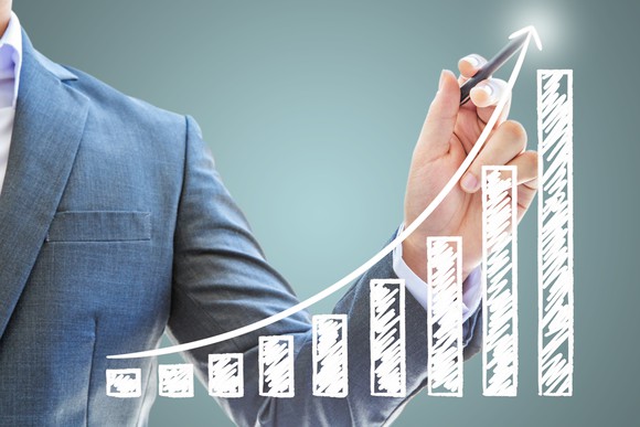 Man in suit pointing to rising stock chart