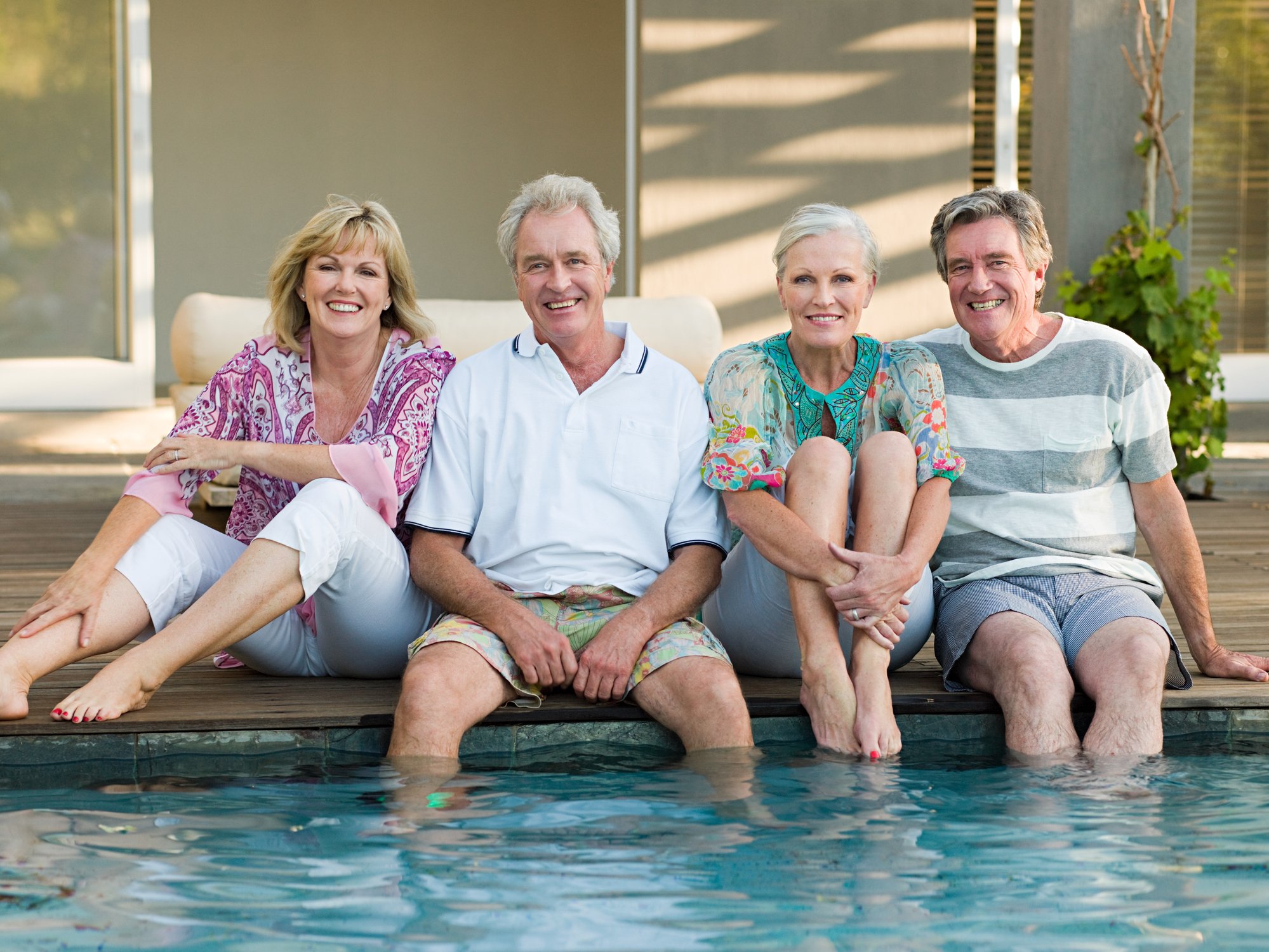 Four suburban baby boomers dipping their feet in a pool.