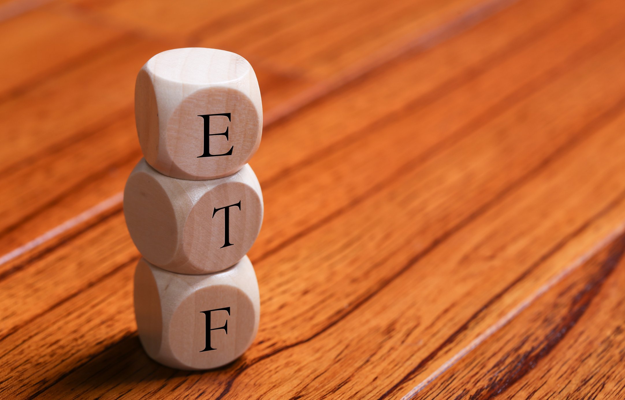 The letters E, T, and F on three dice on top of hardwood floor
