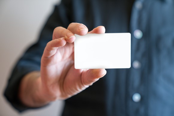 Man's hand holding a blank white card