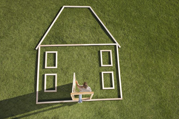 A white outline of a house on a green background with a man walking through the door