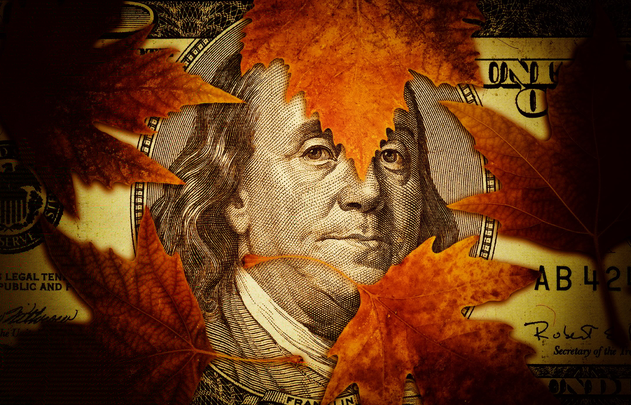 Autumn leaves siting on $100 bill, with Ben Franklin's face showing through.