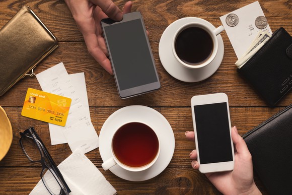 Phones and coffee cups on a table with bank cards visible.