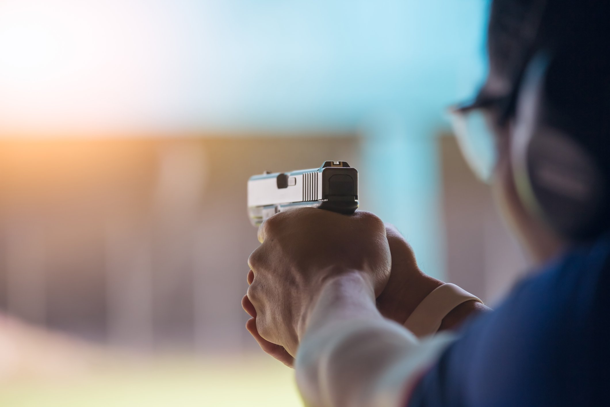 A person shooting a hand gun at a shooting range.