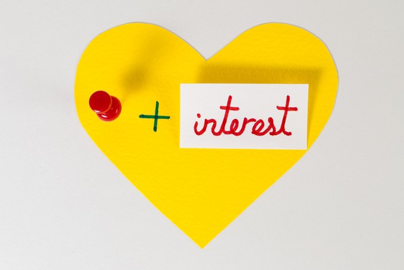 A yellow paper heart containing a pin and the word "interest."