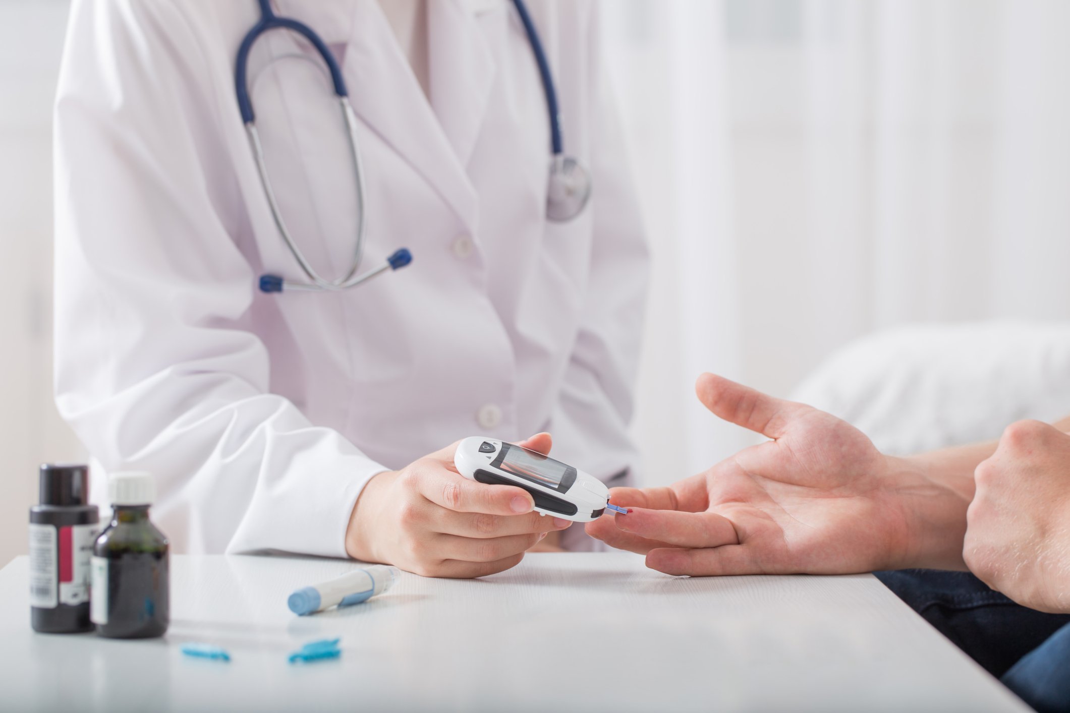 Doctor testing patient's blood sugar with a glucose monitor