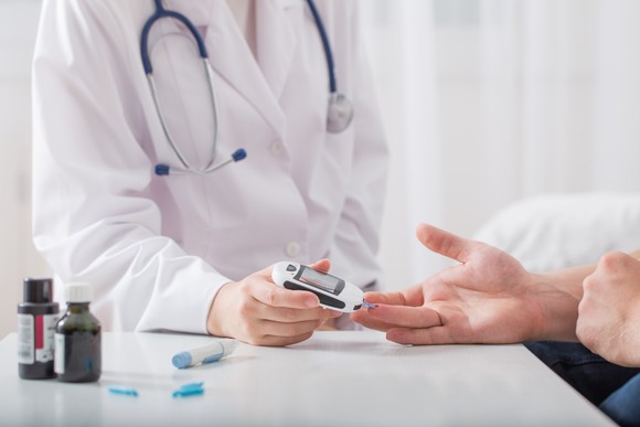 Doctor testing patient's blood sugar with a glucose monitor