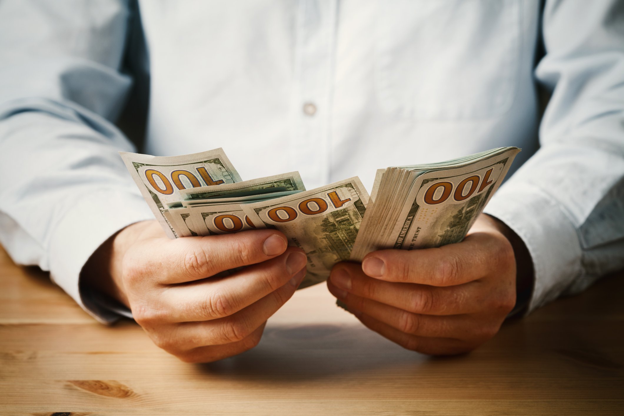 A man counting hundred-dollar bills.
