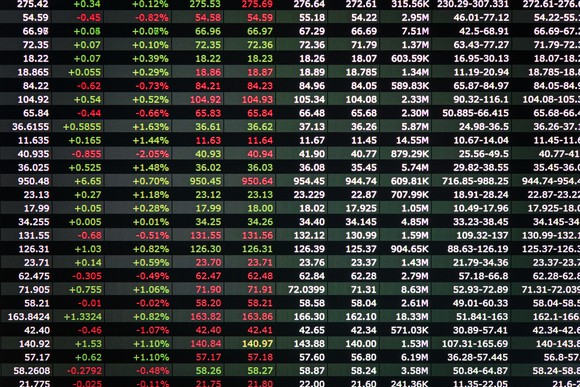 A stock ticker board displays gains and losses.
