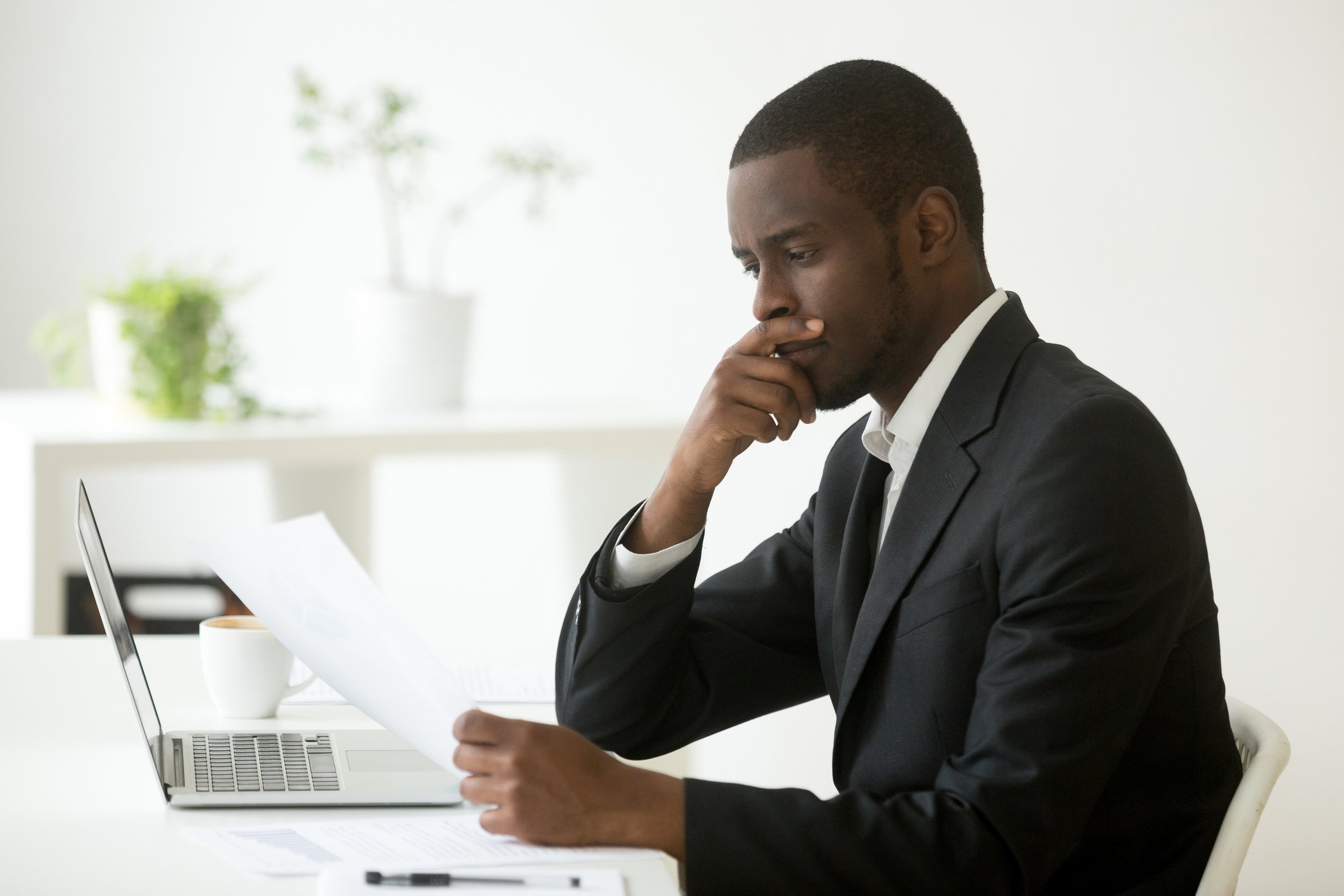 Man looking at paper, with hand on chin
