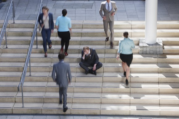 A man sitting on a staircase with people walking past him