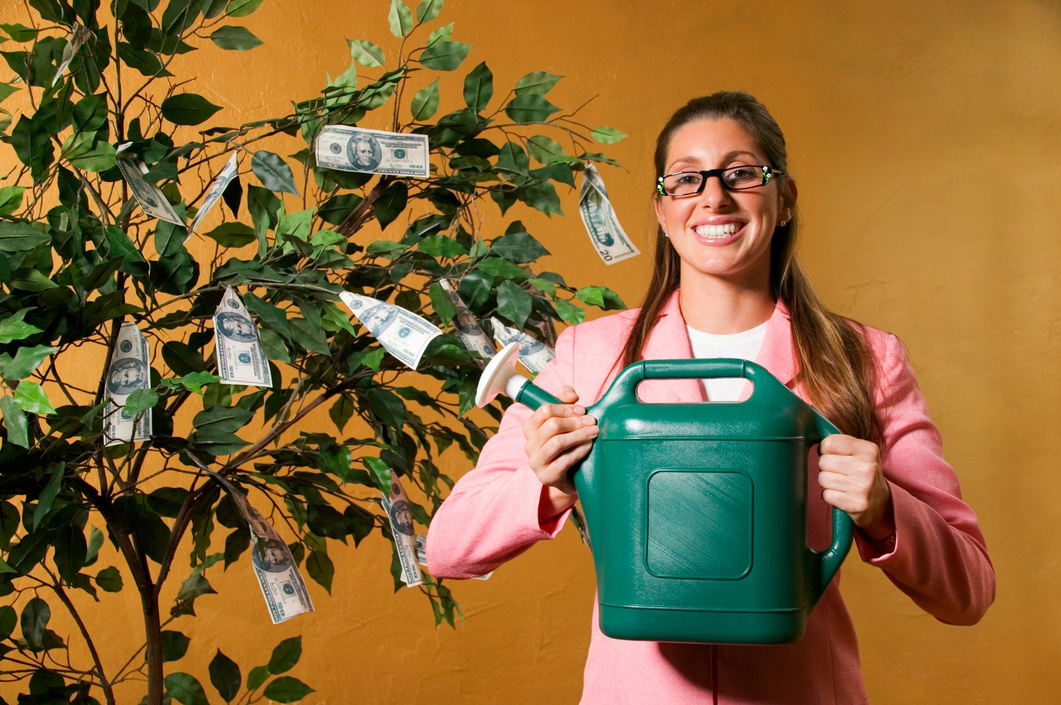 Woman Watering Money Tree Dividends Getty