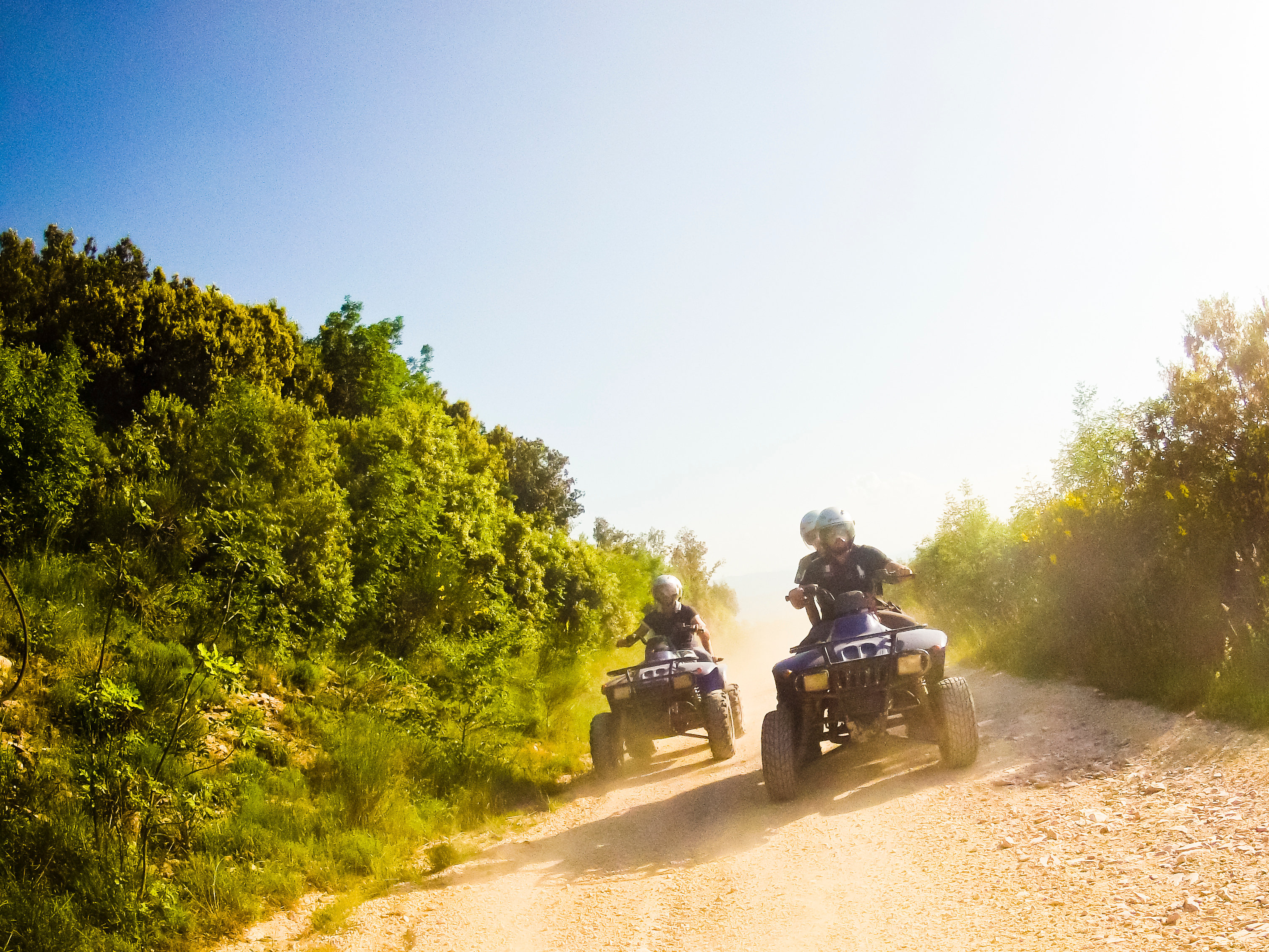 Two people riding ATVs on a dirt road