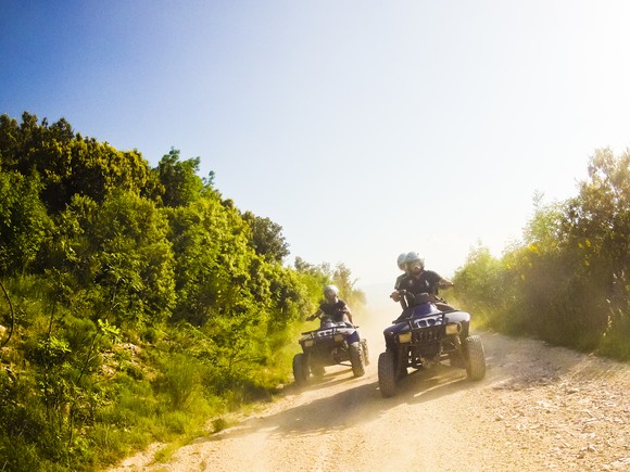 Two people riding ATVs on a dirt road
