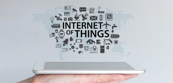 Image a person holding a tablet with the words "Internet of Things" above it and small images of everyday objects above it.