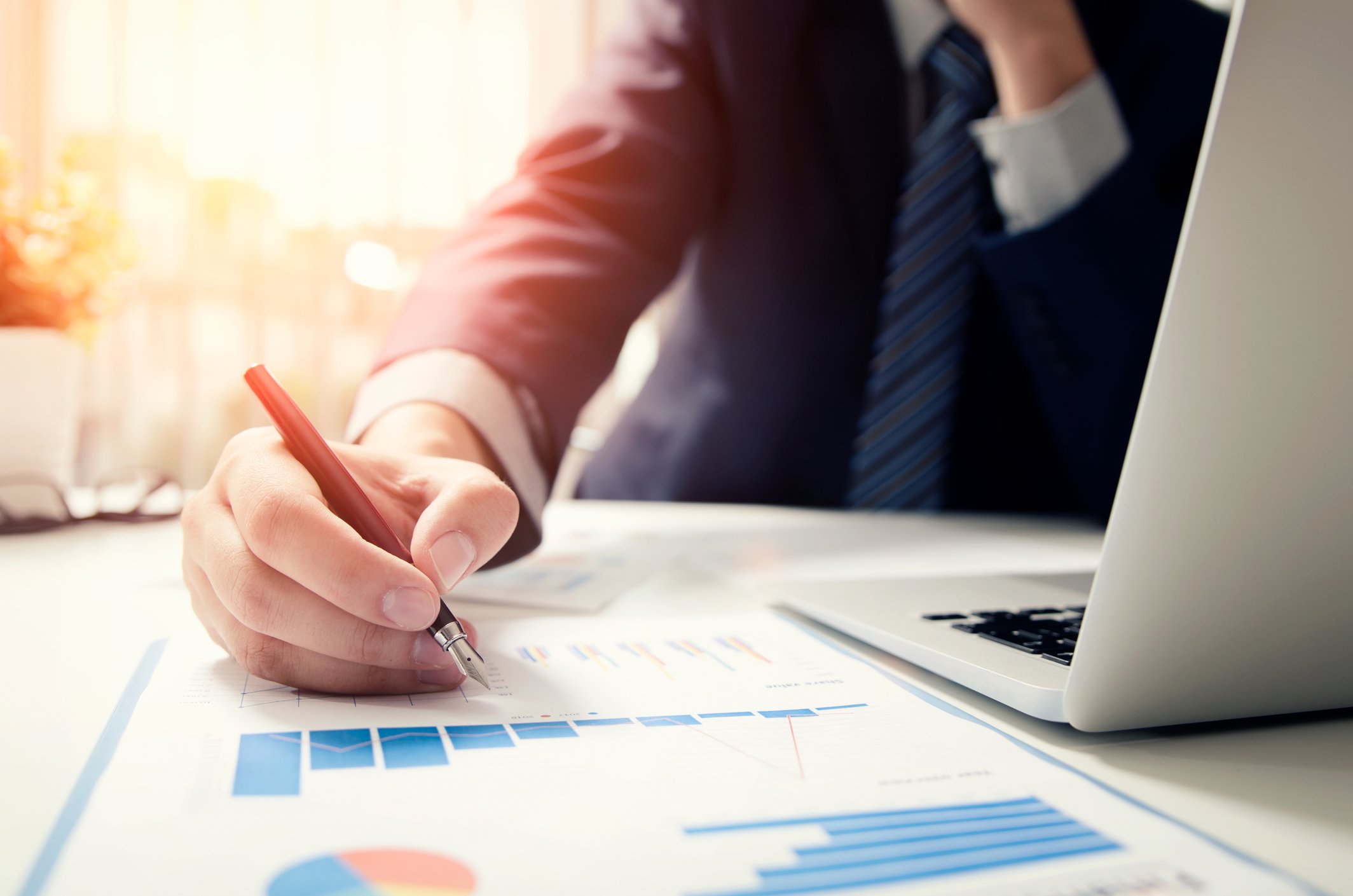 Man working with financial documents and a laptop