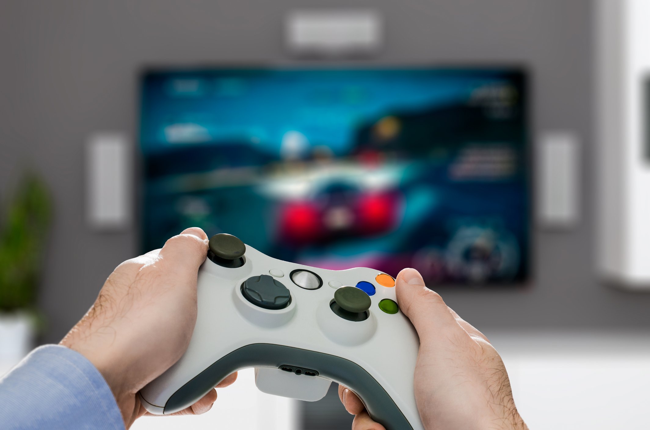 Two hands aim a video game controller at a TV screen displaying the game.