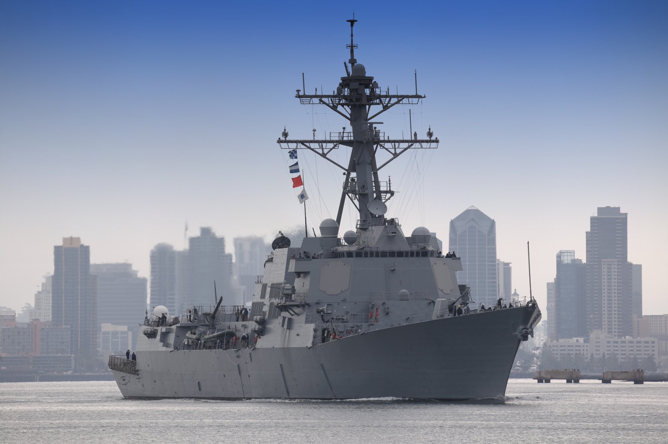 USS Stockdale at sea with a city skyline in the background