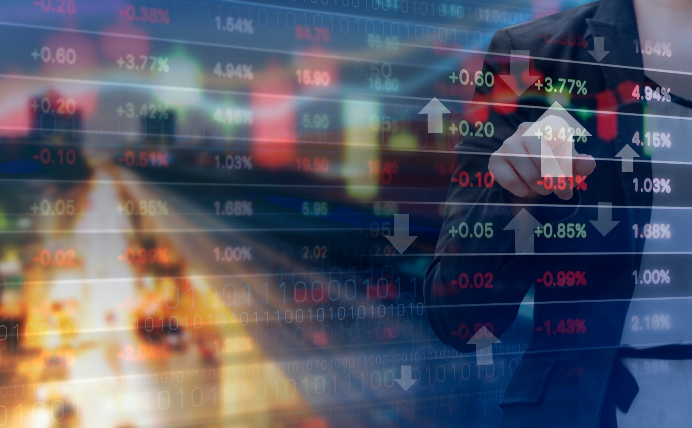 A businessman points to an upward-facing arrow on a financial chart. 