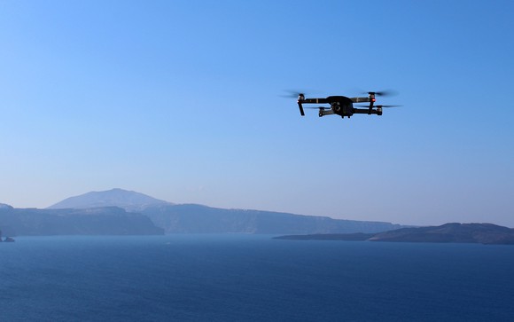 Drone flying over ocean with mountains in the background