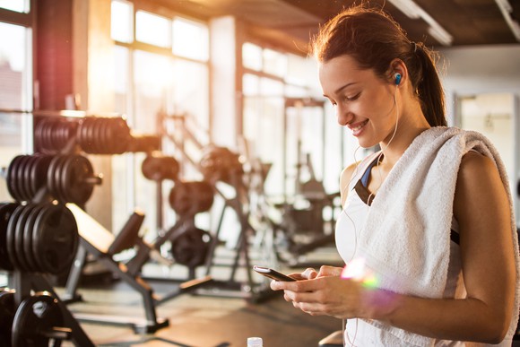A woman taking a break from exercising while looking at her smartphone.