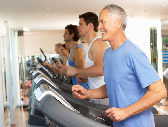 Men and women lined up exercising on treadmills.