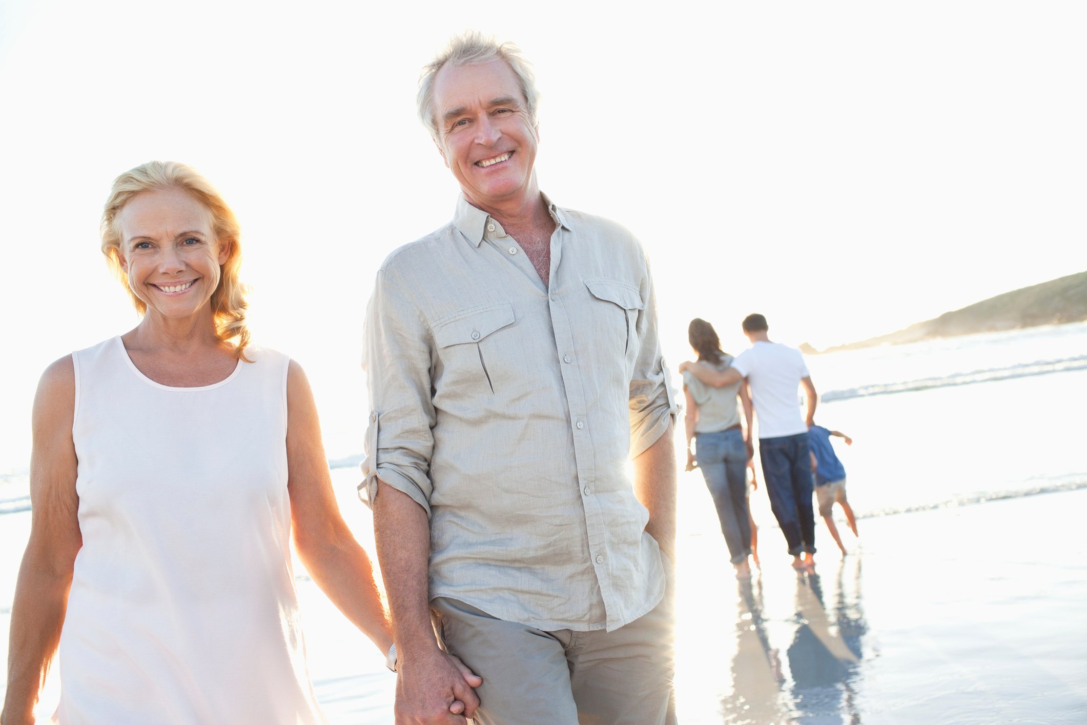Male and female couple in their 60s walking on the beach.