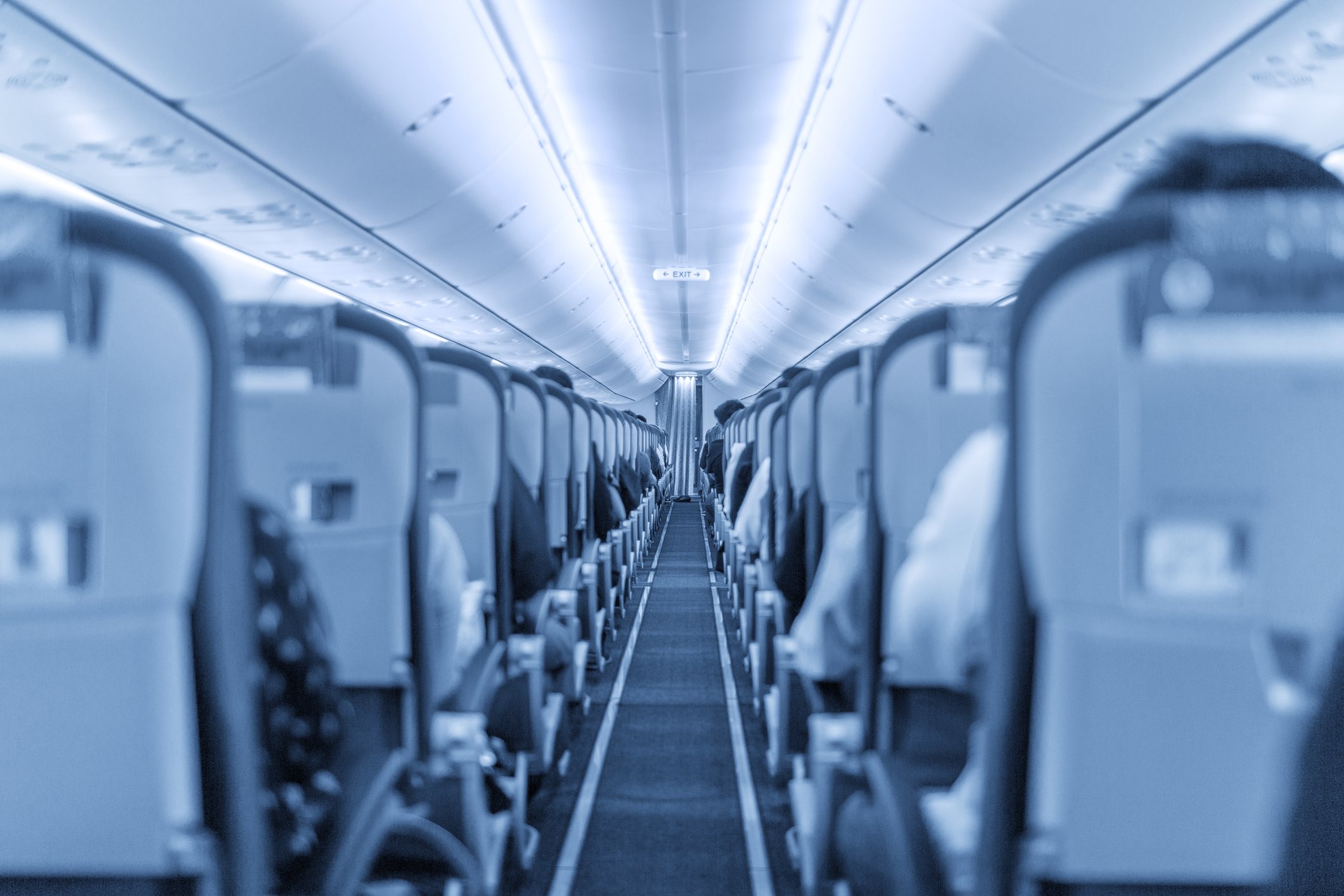 Looking down the interior aisle of a plane, with seats on either side