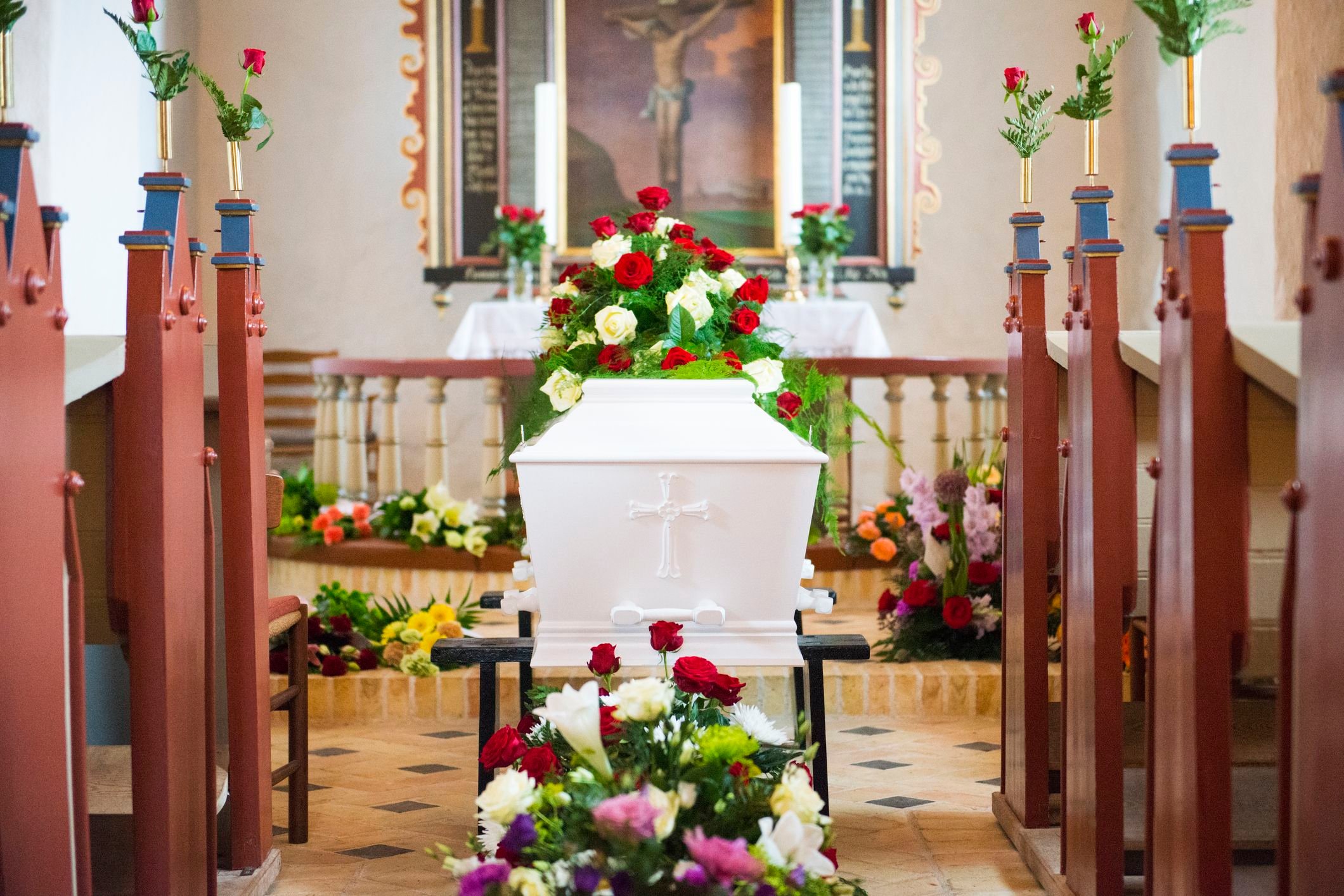 White coffin covered in flowers inside church