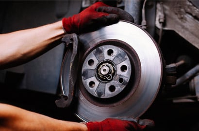 Gloved hands on a car brake and rotor.
