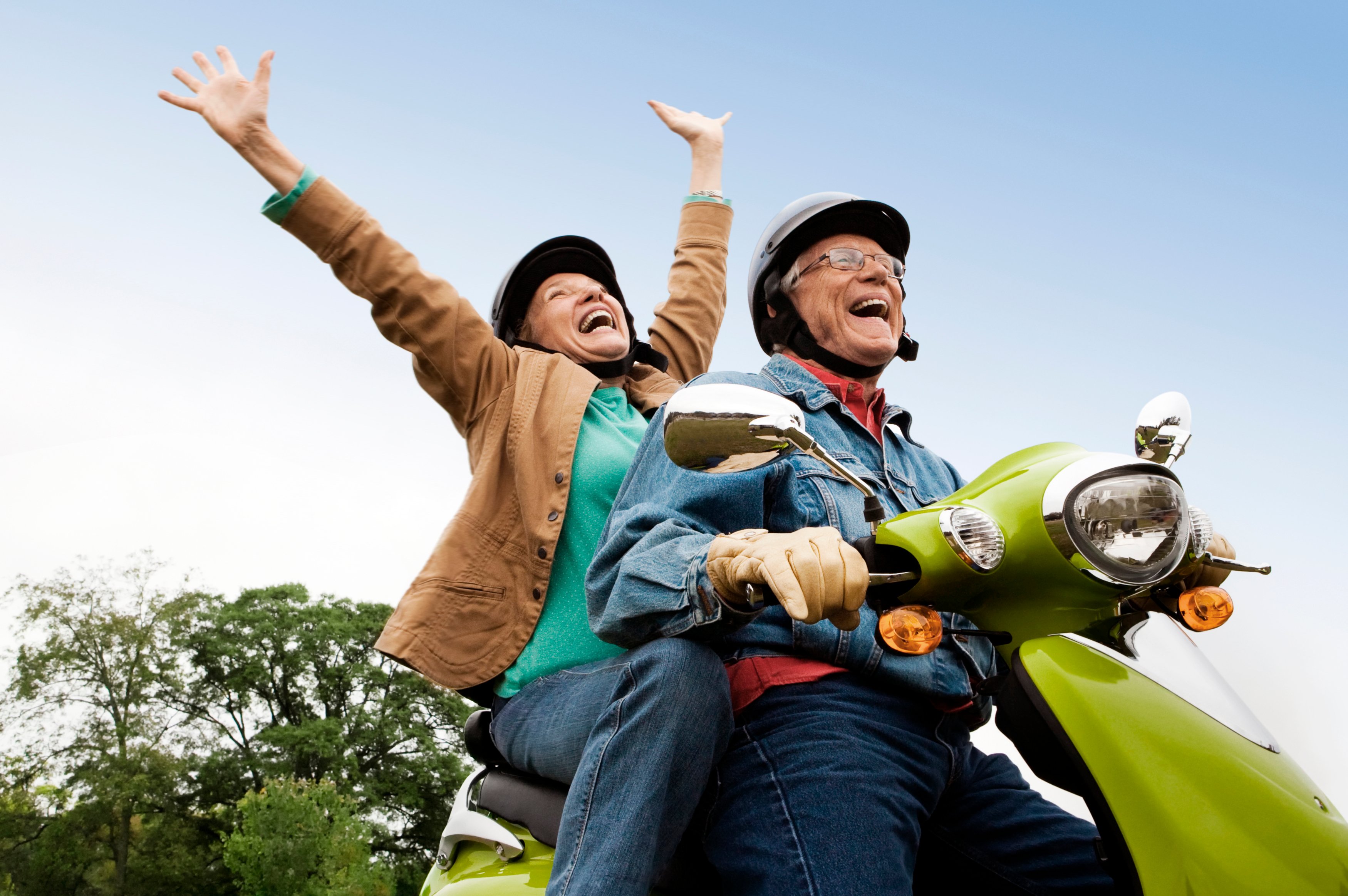 Retired couple riding on a scooter.