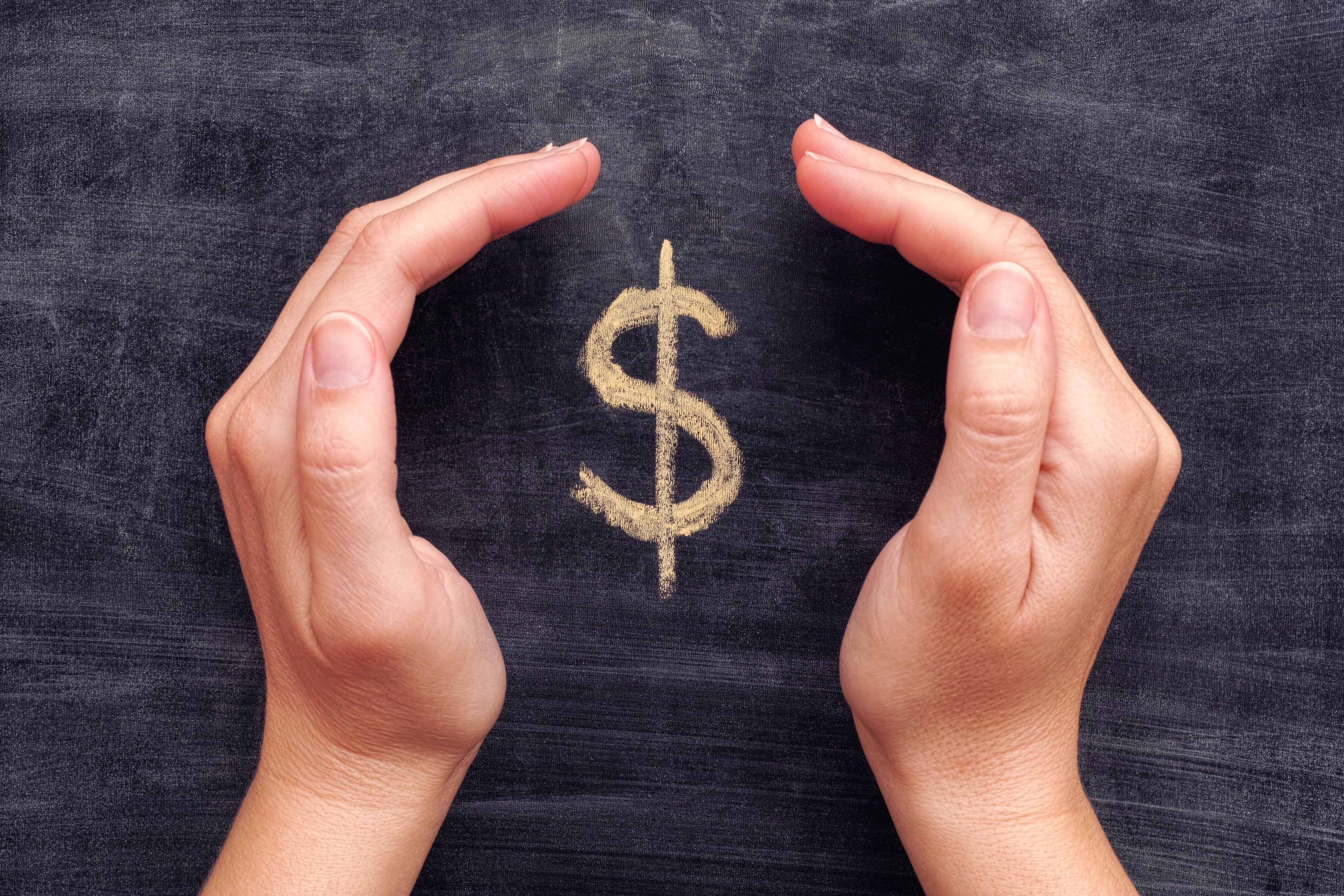Cupped hands framing a dollar sign written on a blackboard.