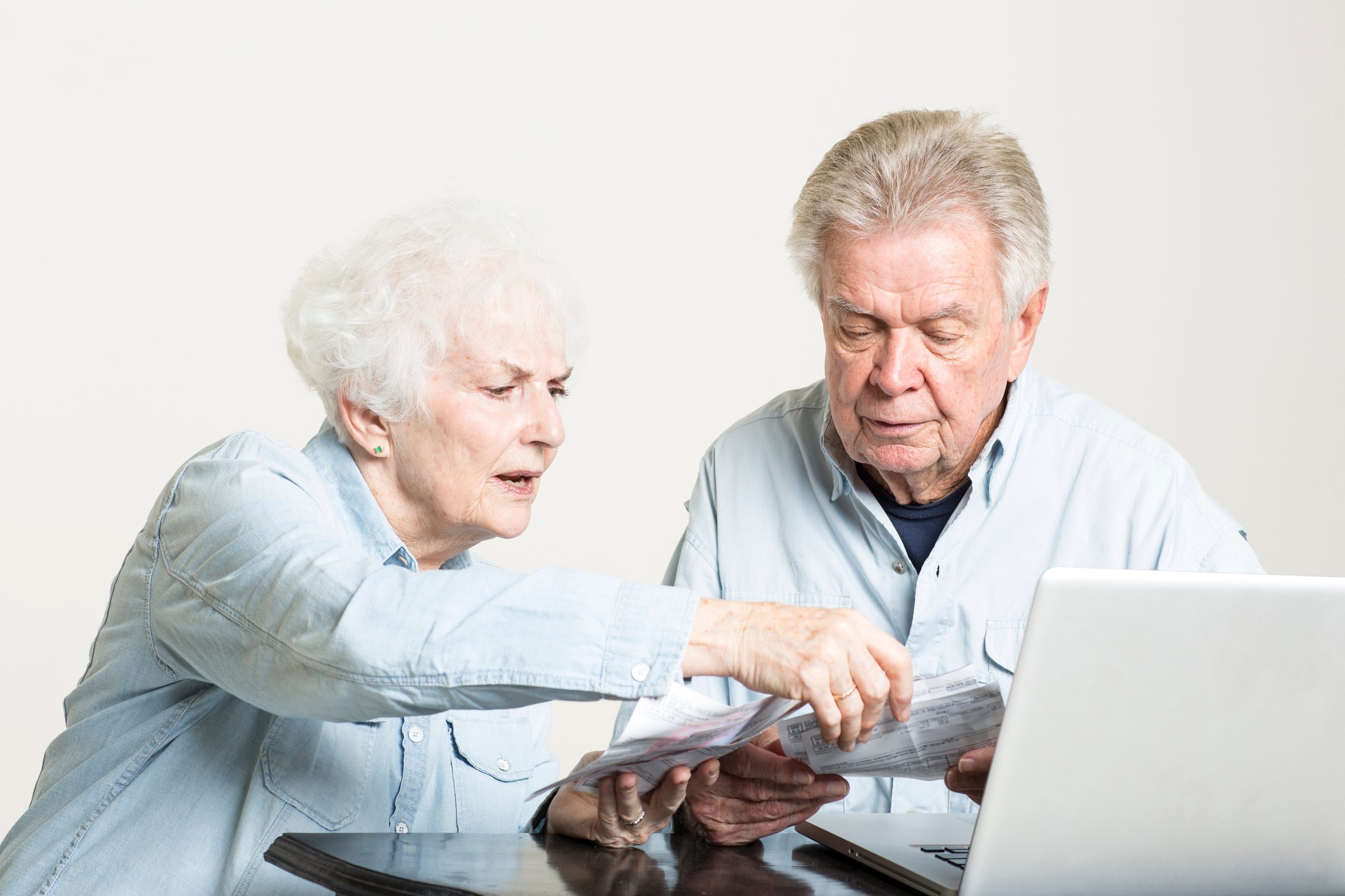 Senior couple looking worried while sorting through financial accounts.