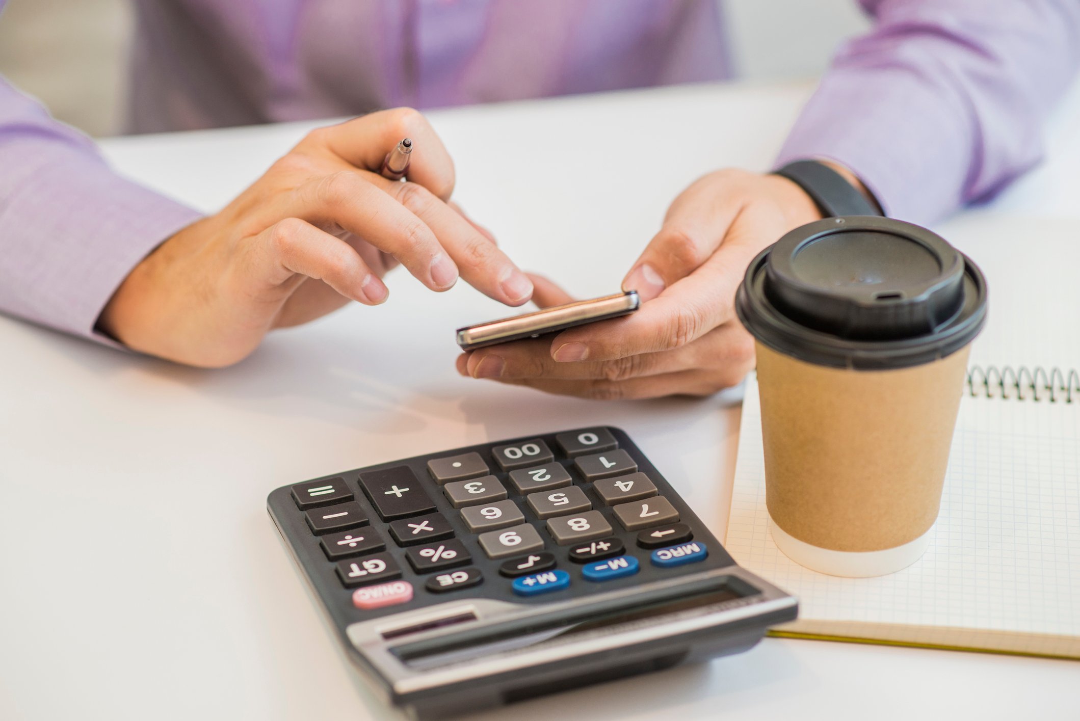 Human hands typing on a calculator.