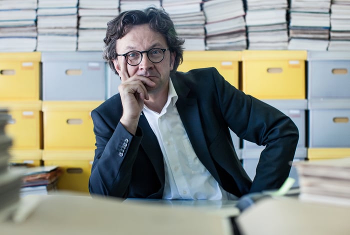 Business owner sitting in front of a stack of boxed paperwork. 