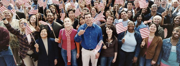 Crowd of people with American flags looking up.