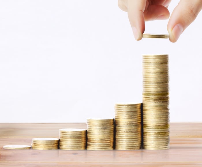 Image of a hand stacking growing piles of coins