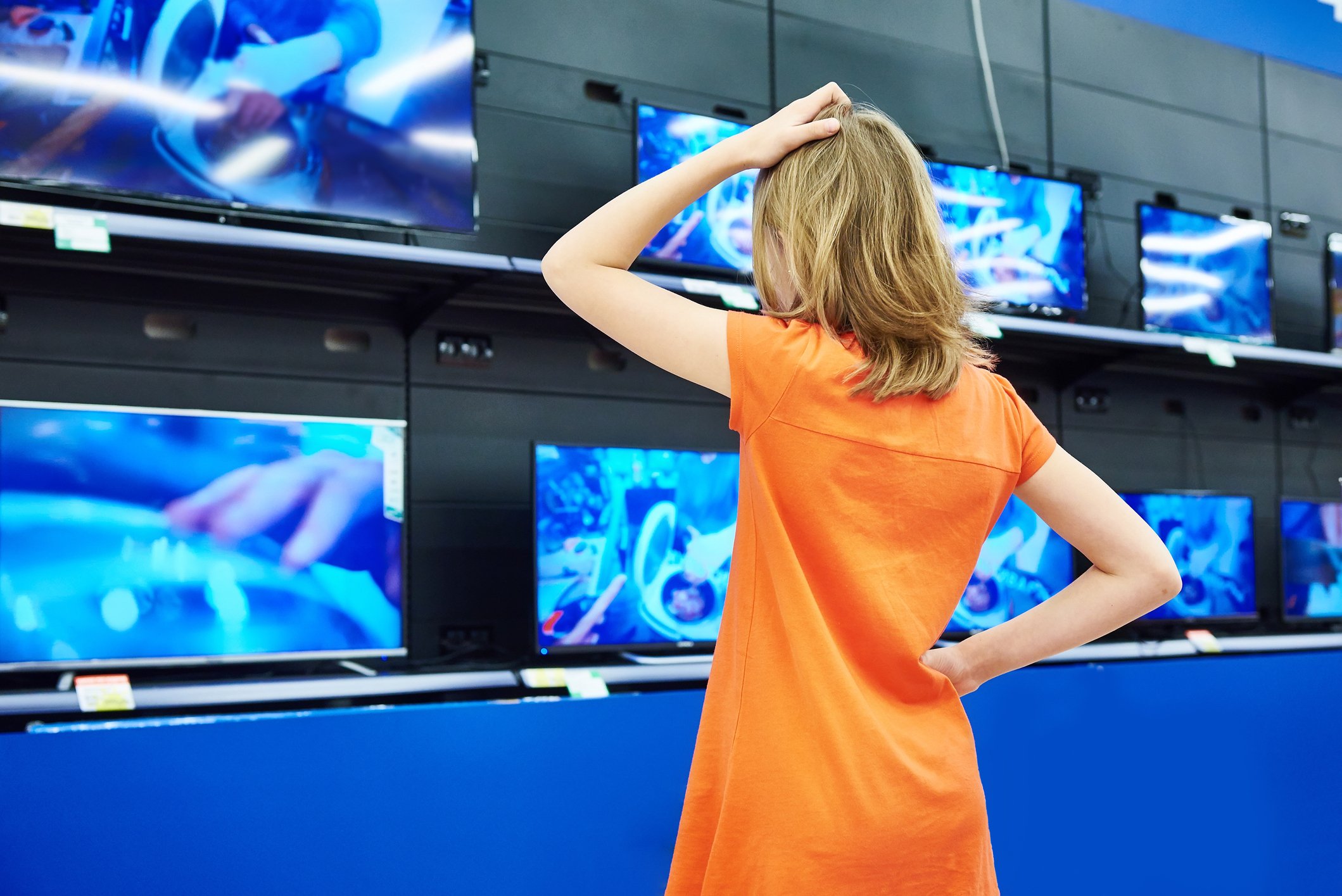 Woman looking at televisions on display.