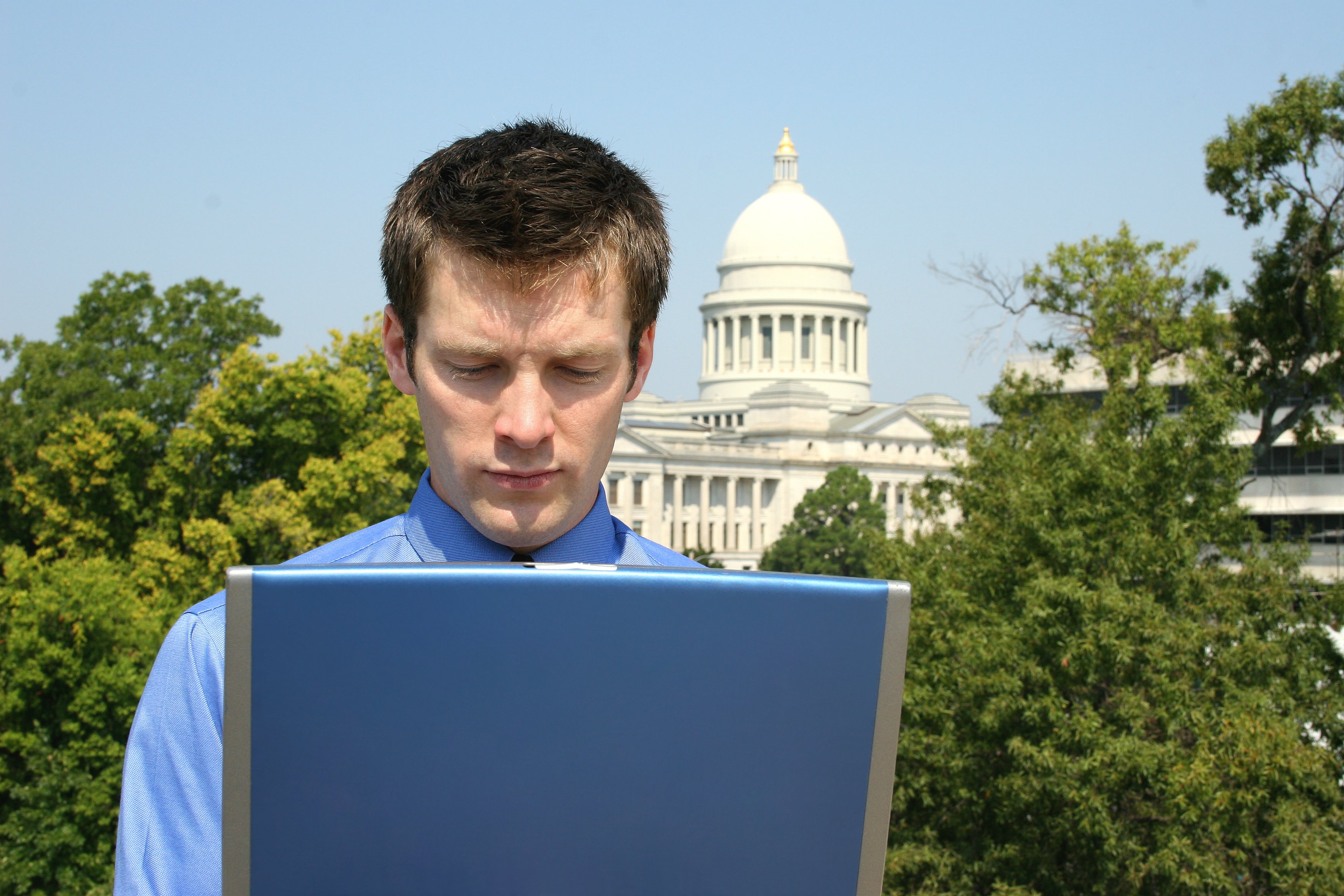 Man on computer in front of government building
